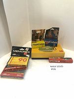 View of multiple items including Kodak flash bulbs, cassette tapes, pen, and VagiCubes box