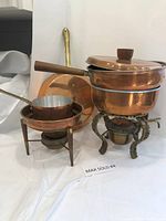 Full lot showing two copper chafing dishes with ornate stands, two fry pans (one with lid), and one small pot.