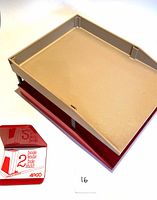 Two stackable desk trays shown from top and angled side views, beige and red plastic trays with slight wear.