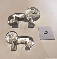 Top-down view showing both the medium and small clear glass lion figurines side by side with a note displaying the number 10.