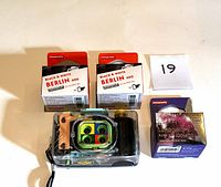 Photo showing the Lomography Action Sampler camera in a waterproof case with three rolls of film: 2x Lomography Berlin Black & White 400 film and 1x Lomography Lomochrome Purple 100-400 film.