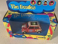 Front view of Beatles-themed collectible toy car in original box with psychedelic design on packaging.
