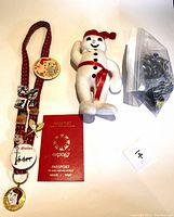 Lot overview including Bonhomme doll, lanyard with pins/buttons, Expo '67 passport, and bag of marbles