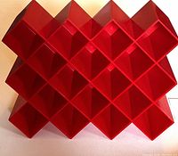 Front view of red plastic vintage Copco spice rack showing 18 square compartments arranged in a lattice pattern.