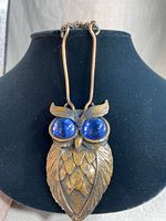 Copper owl pendant with large blue Murano glass eyes displayed on black bust with chain link copper necklace.