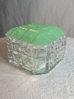 Closed view of square box with jadeite green textured lid fitted on clear textured crystal base.