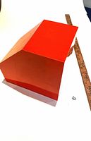 Photo showing the top and angled side of the large orange/red laminate bookend, with a wooden ruler indicating size
