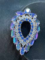 Front angle of vintage Sarah Coventry brooch showing teardrop shape and iridescent blue marquise rhinestones with blue and clear round rhinestones inside.