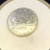 Close-up photo of the 1978 Canadian one dollar coin showing two individuals paddling a canoe with the year and denomination inscribed.