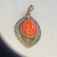 Front view of the large oval oxblood coral cabochon in silver filigree pendant showing color and surface details.