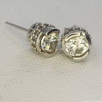 Close-up photo of one pair of 925 sterling silver stud earrings with large clear round gemstones and smaller stones along the sides in a decorative setting.