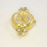 Close-up of gold-tone vintage Clossi watch face with rhinestone embellishments on top and bottom. Shown without bracelet.