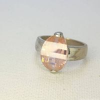 Front angle view of the ring showcasing the pear-shaped pink sapphire mounted on a sterling silver band.