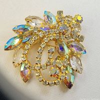 Top view of gold tone vintage brooch with colorful AB crystals and clear rhinestones in leaf and swirl floral pattern