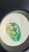 Green dial watch with ladybug graphic on dial and green strap shown through round opening.