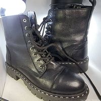 Side and front angle of pair of black Aldo leather boots with studded trim and laces.