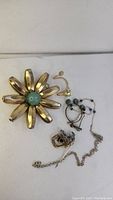 Overview of lot including gold-tone flower brooch, bird pendant, small earrings, broken post, and silver chain necklace