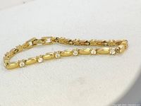 Photo showing the full length of the vintage tennis bracelet with gold-tone links and clear rhinestones.