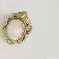 Close-up view of the Whiting & Davis mother of pearl ring showing the decorative metal frame and central pearl stone.
