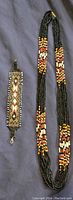 Photo of the indigenous beaded necklace and bracelet side by side on a fabric background, highlighting bead colors and pattern.