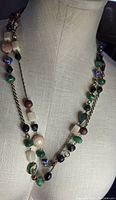 Full view of the double strand necklace on a display bust showing bead variety and chain detail.