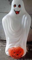 Front view of the white blow mold ghost figure with orange pumpkin base, showing the ghost's facial features and draped plastic design.