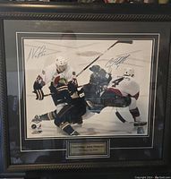 Framed, matted photo of NHL players Chris Phillips and Anton Volchenkov in action with two player signatures on the glass.
