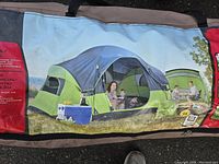 Picture of the tent's packaging showing an assembled tent on grass with people beside it, illustrating its size and shape.