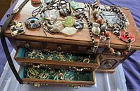 Top view of open drawers filled with assorted jewelry on and inside a large wooden jewelry box