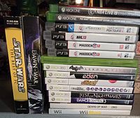 Stack of video game cases for Xbox One, PS3, Xbox 360, Wii, and PC including NBA Live 19, Madden NFL titles, Batman Arkham City, Gears of War, and others.