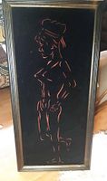 Front of framed vintage velvet art showing a stylized woman silhouette in profile on a black velvet background with a dark wood frame.