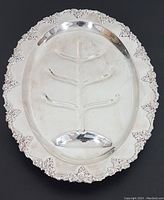 Oval vintage silver plate meat platter with ornate decorative border and embossed branch design visible.