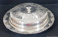Silver plated serving dish with ornate Old English engraving and domed lid, side view