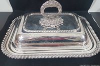 Front angle view showing the silver plated serving dish with lid and elaborate handle, including detailed edge trim.