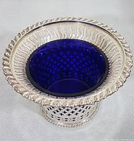 Top view showing ornate rim with leaf and wave pattern, lattice pierced sides, and cobalt blue glass insert inside.