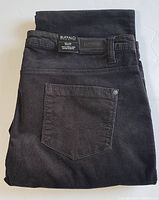 Folded dark grey corduroy pants showing back pocket and waistband label with brand information and size tag indicating size 14 and regular cut.
