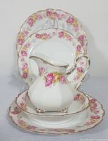 Five-piece Limoges porcelain set featuring floral patterns and gilded edges: creamer, nappie, two side plates, salad plate