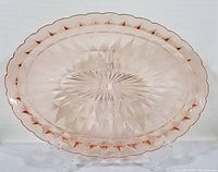 Pink glass oval platter displaying Windsor pattern with starburst and geometric designs, scalloped edges, and translucent pink color.