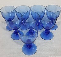 Eight cobalt blue blown crystal goblets arranged together showing full set and color.
