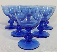 Front angled view of six Nybro cobalt blue crystal goblets arranged in a cluster.