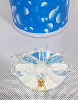 Top-down view of clear faceted crystal dragonfly figurine with gold accents on mirrored base showing wing and body details.