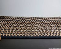 Full view side of the rug showing flat woven zigzag pattern in black and natural jute color.