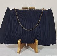 Front close-up of the vintage black silk evening bag showing pleated fabric, gold-tone clasp with clear acrylic knobs, and chain.