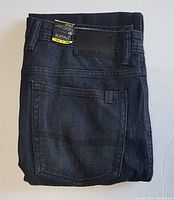 Folded jeans displaying back pocket and branded leather patch on waistband.