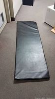 Full view of black exercise mat or exam table top showing length and surface texture.