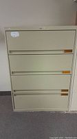 Front view of beige 4-drawer filing cabinet showing drawer fronts and label holders.
