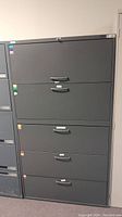 Front view of the large black 5 drawer filing cabinet showing all closed drawers with handles and label holders.