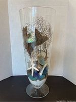 Front view showing clear glass vase with starfish, shells, sea fan coral, and decorative stones inside.