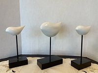 Set of three white decorative sculptures (two birds and one whale) mounted on black stands with metal rods, shown against a plain backdrop for clear viewing.
