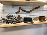 Shelf with two decorative branches, wooden bowl, small wood pieces, and knotted wood piece